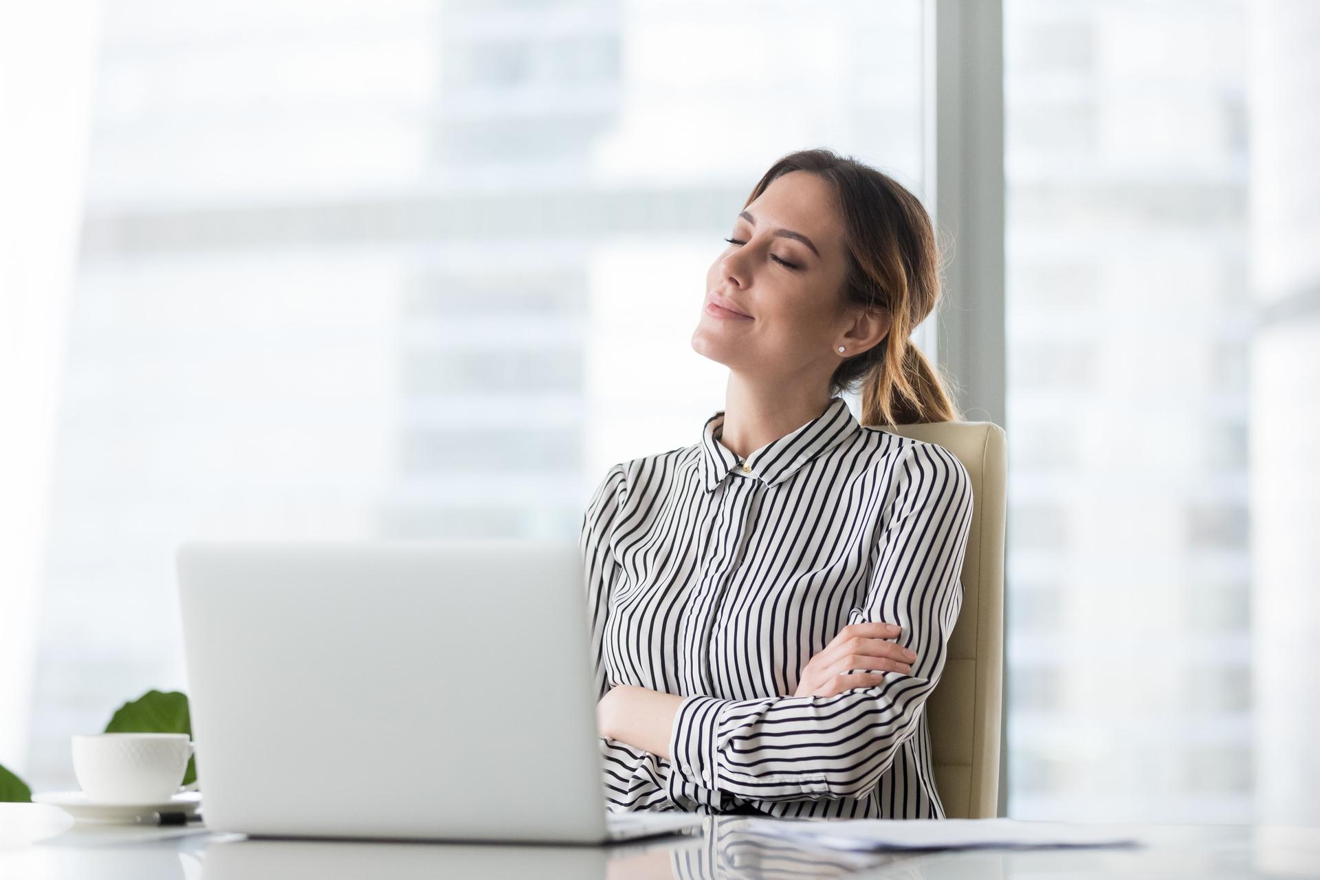 Smiling female boss relaxing in office chair with eyes closed